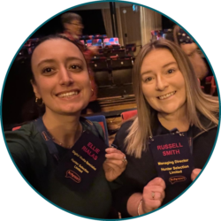 Two professionals at an industry event holding conference name badges and posing for a photo.