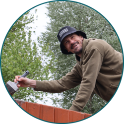 Employee painting an outdoor fence as part of a volunteering and community engagement project.
