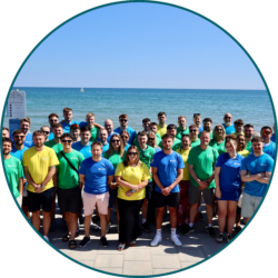 Large group of employees standing together by the seaside during a company team-building and culture event.