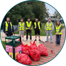 Employees wearing high-visibility vests taking part in a community litter pick with bags of collected waste.
